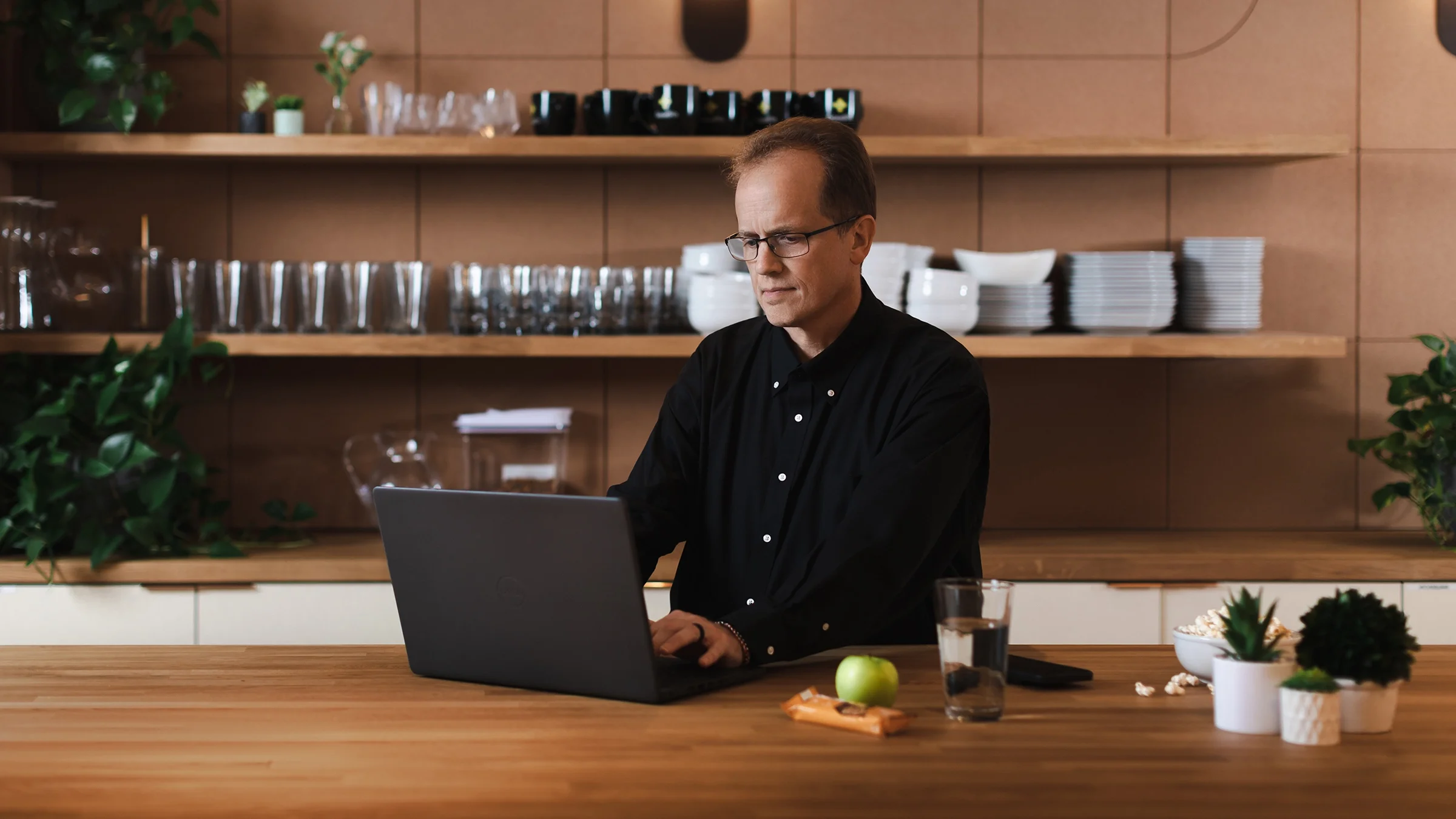 Roger Hare en su computadora portátil en la cocina. Tiene refrigerios saludables a su lado.