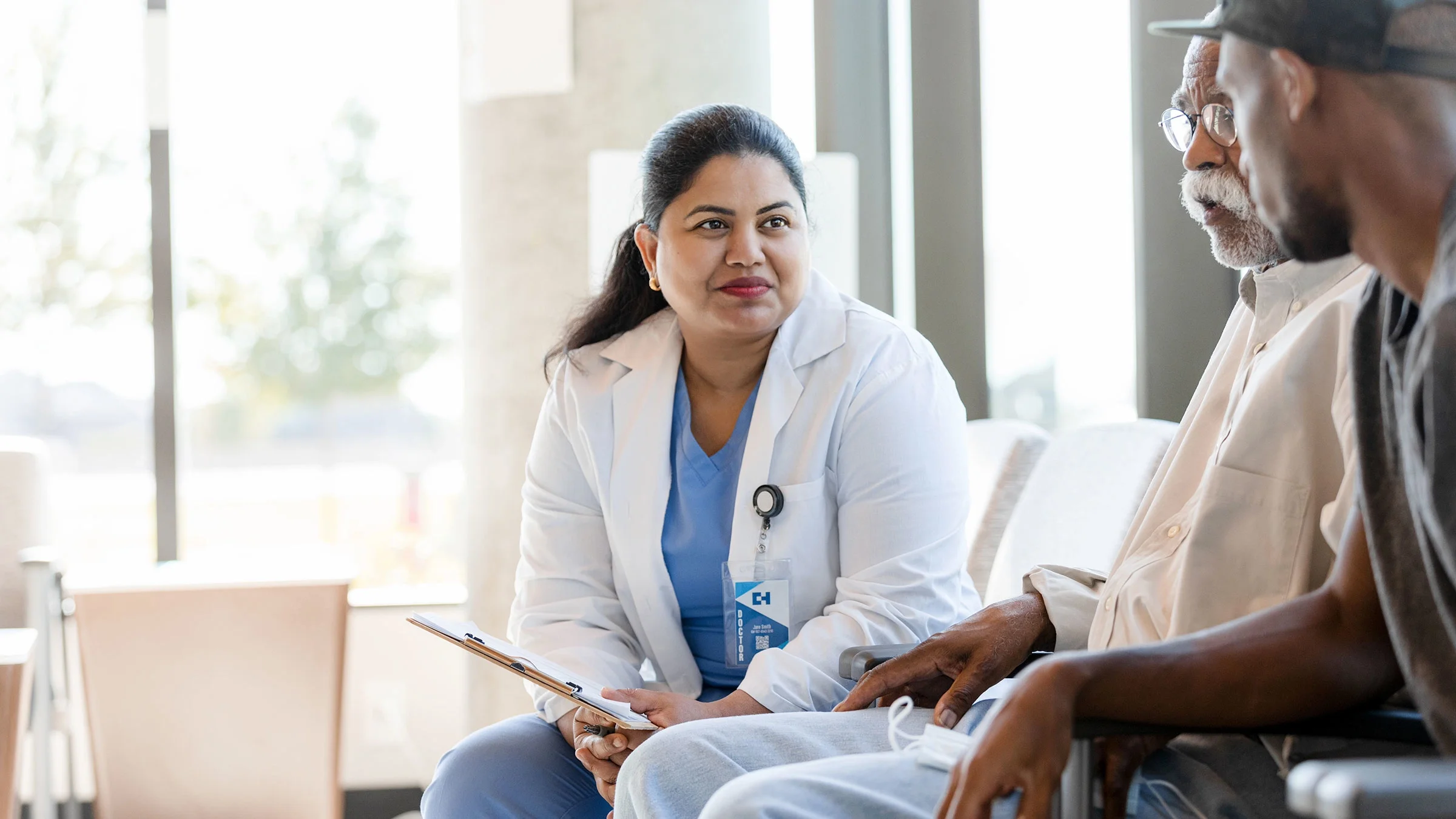 A senior patient and his loved one meet with a healthcare professional.