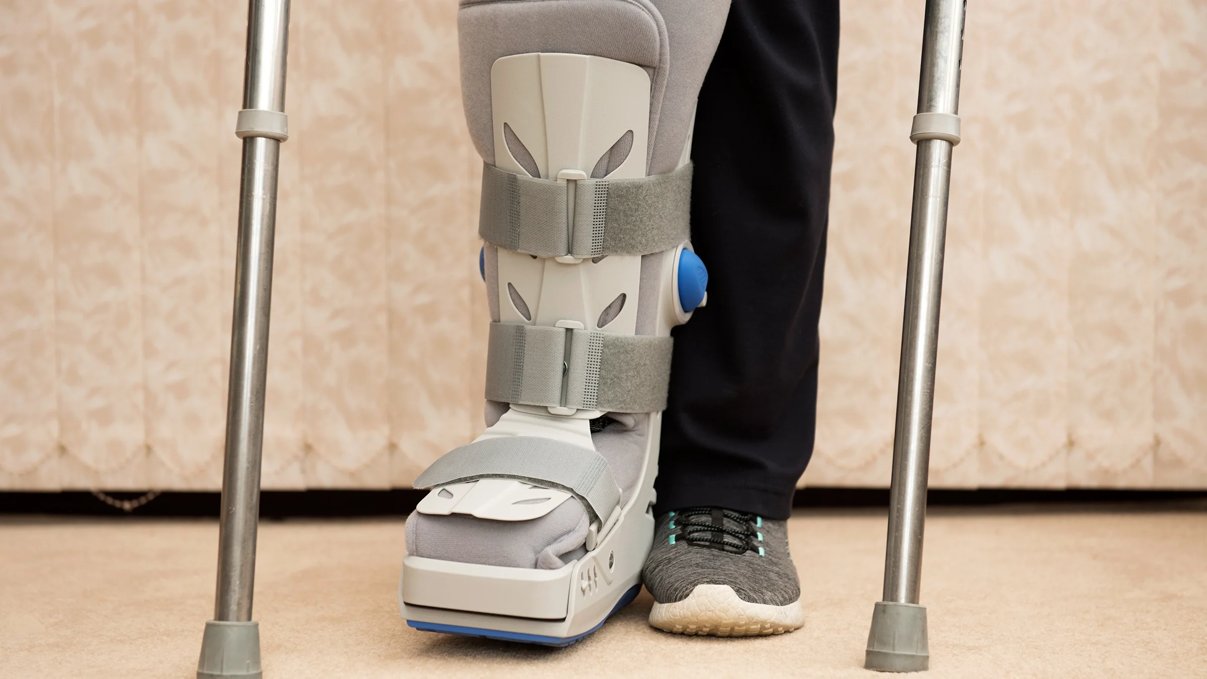 A woman stands on crutches while wearing a medical orthopedic boot.