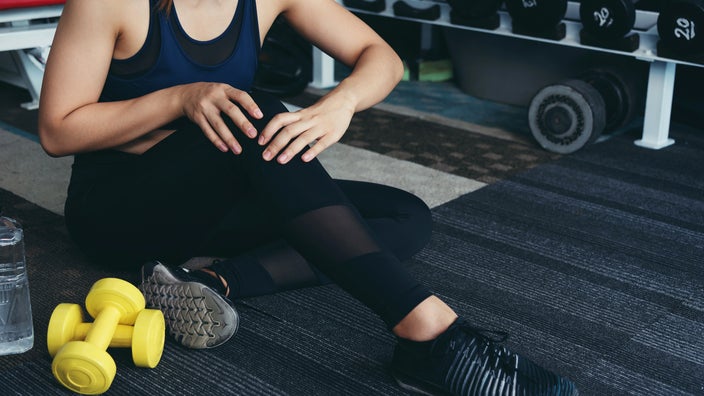 Cropped shot of a person tending to their sore knee at the gym.