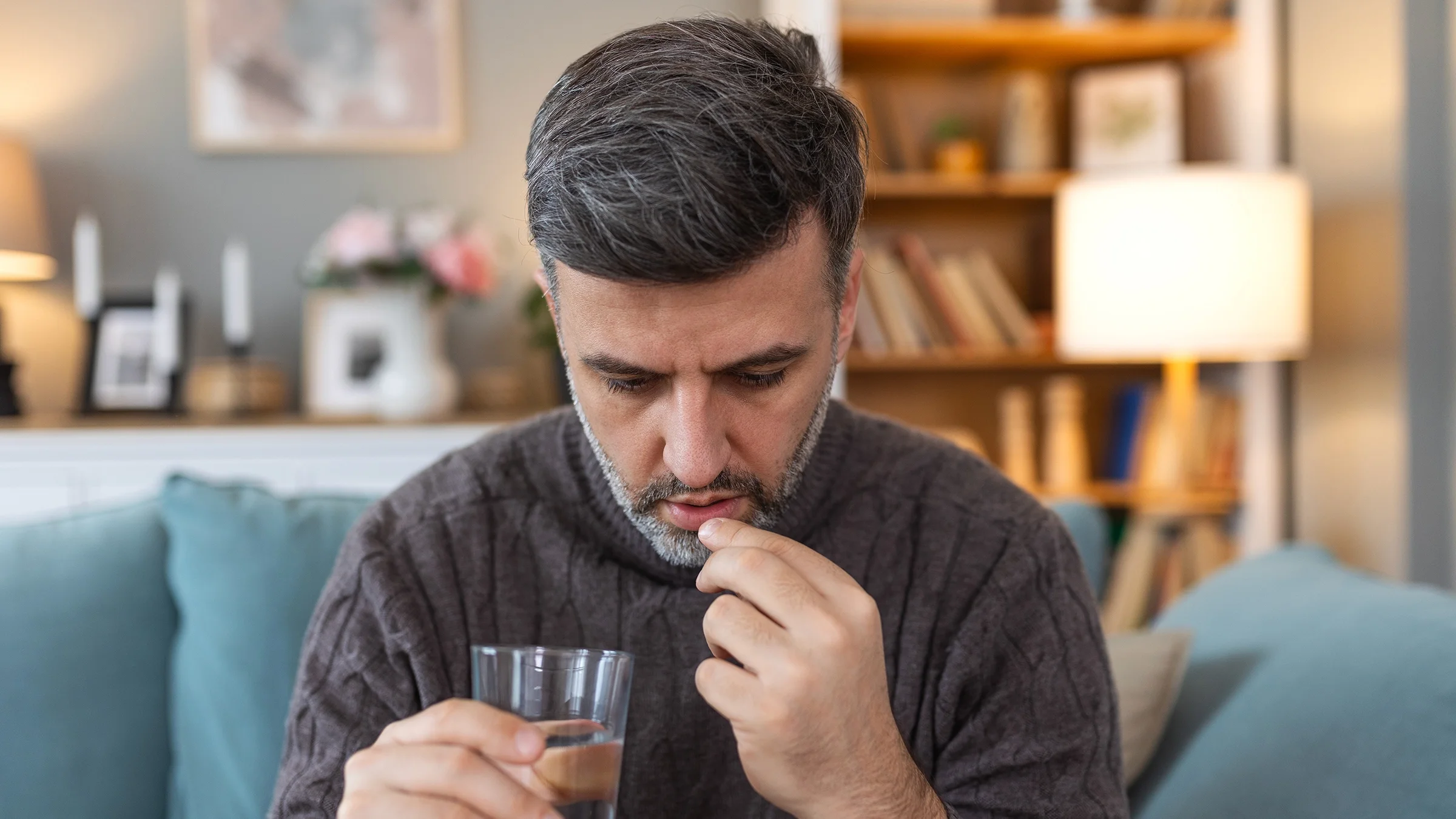 A man takes an oral medication at home.