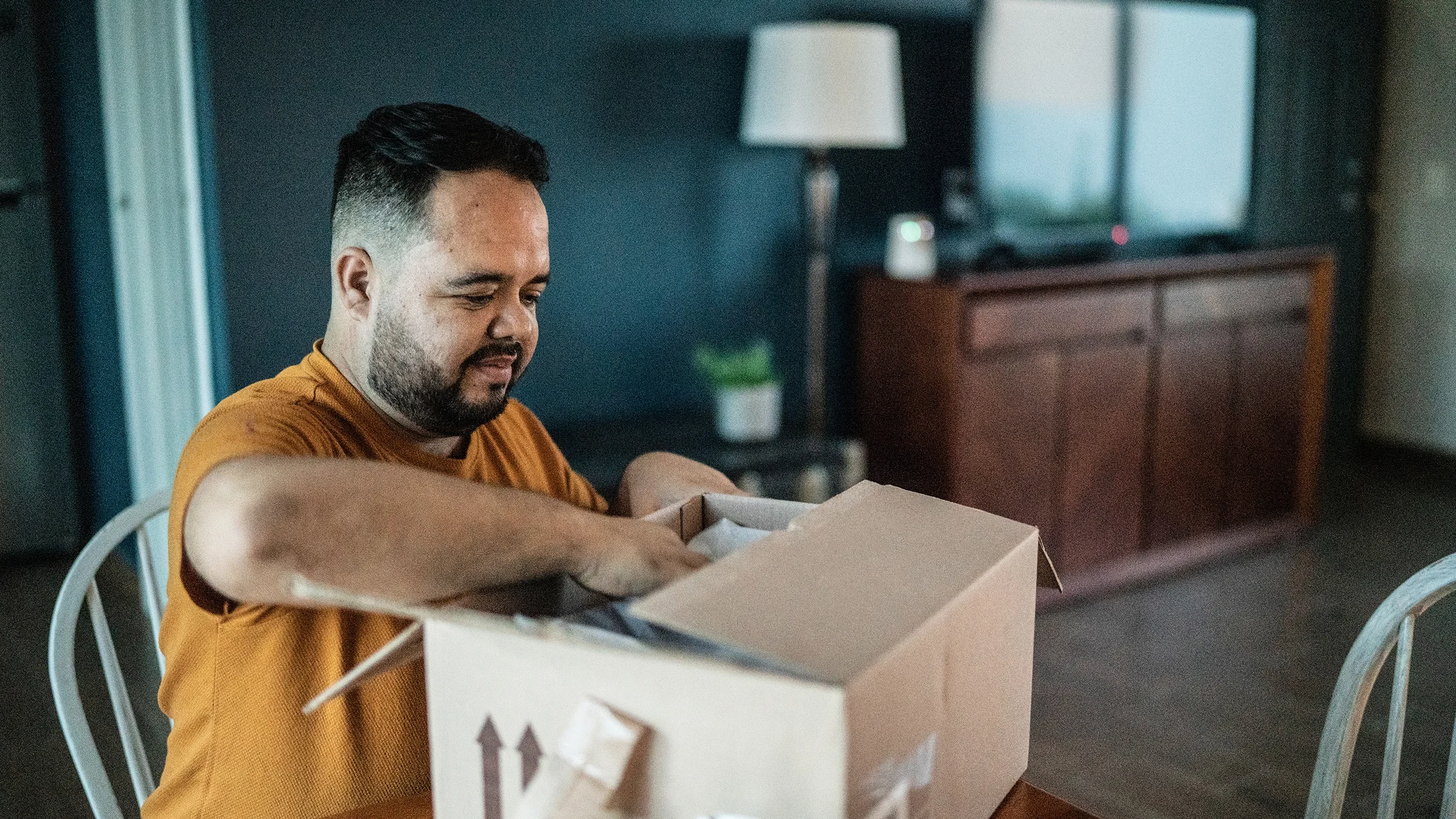 Man opening package in the dining room at home.