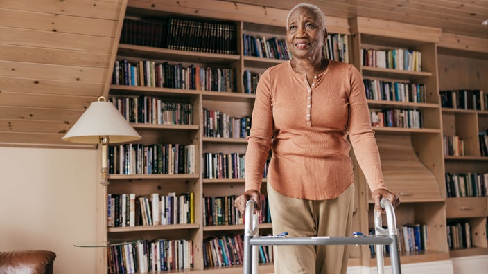 A woman is at home using her walker.