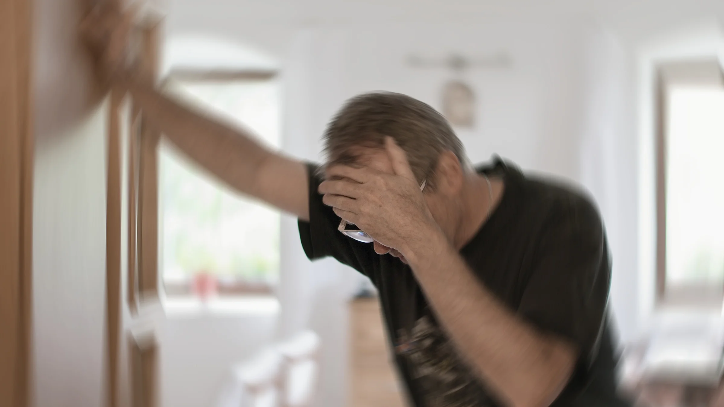 A man grabs his forehead as he experiences dizziness. Feeling dizzy and having balance problems is one of the early signs of a ministroke.