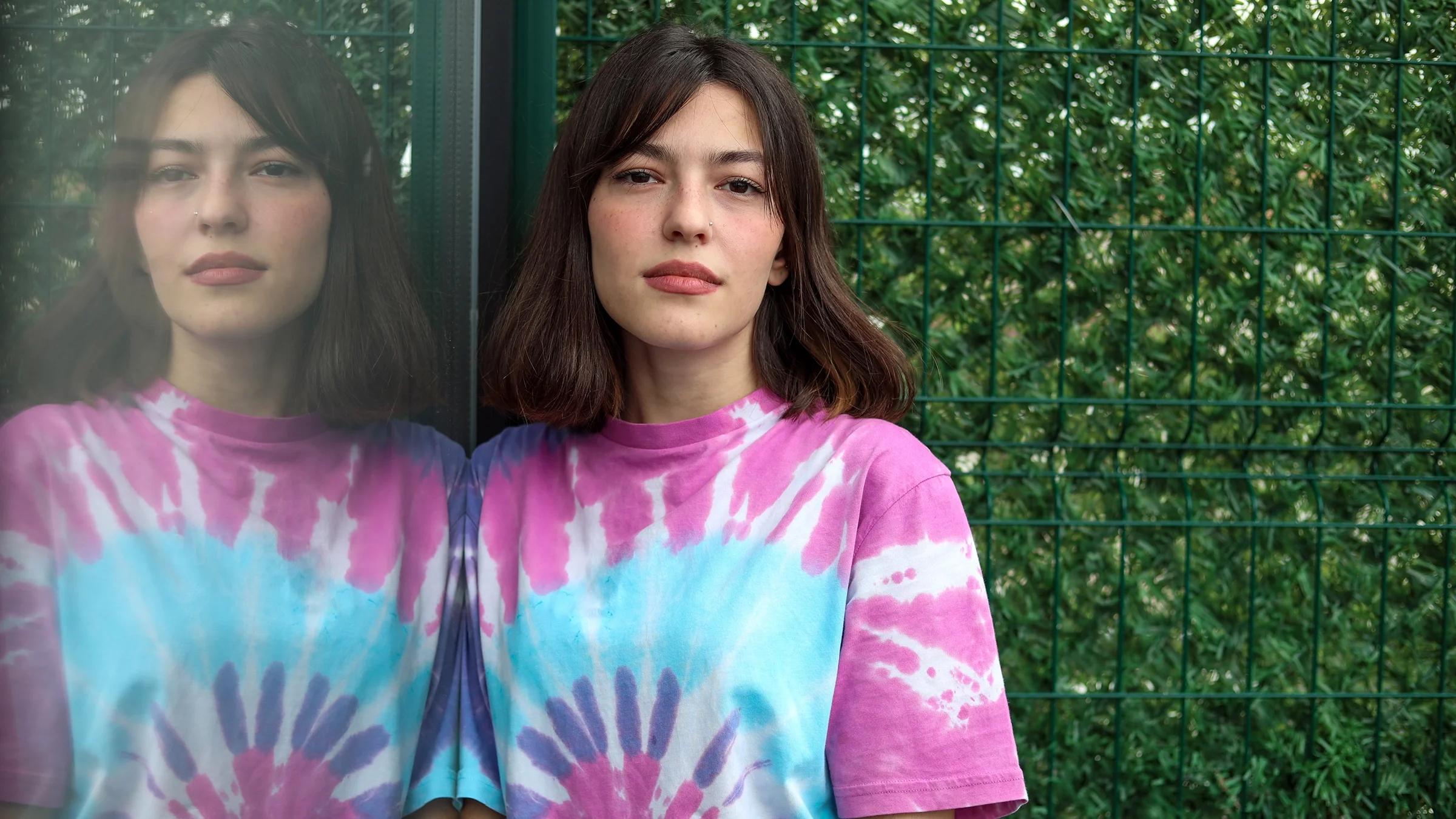 Portrait of a young woman with long dark hair in a tie dye t-shirt.