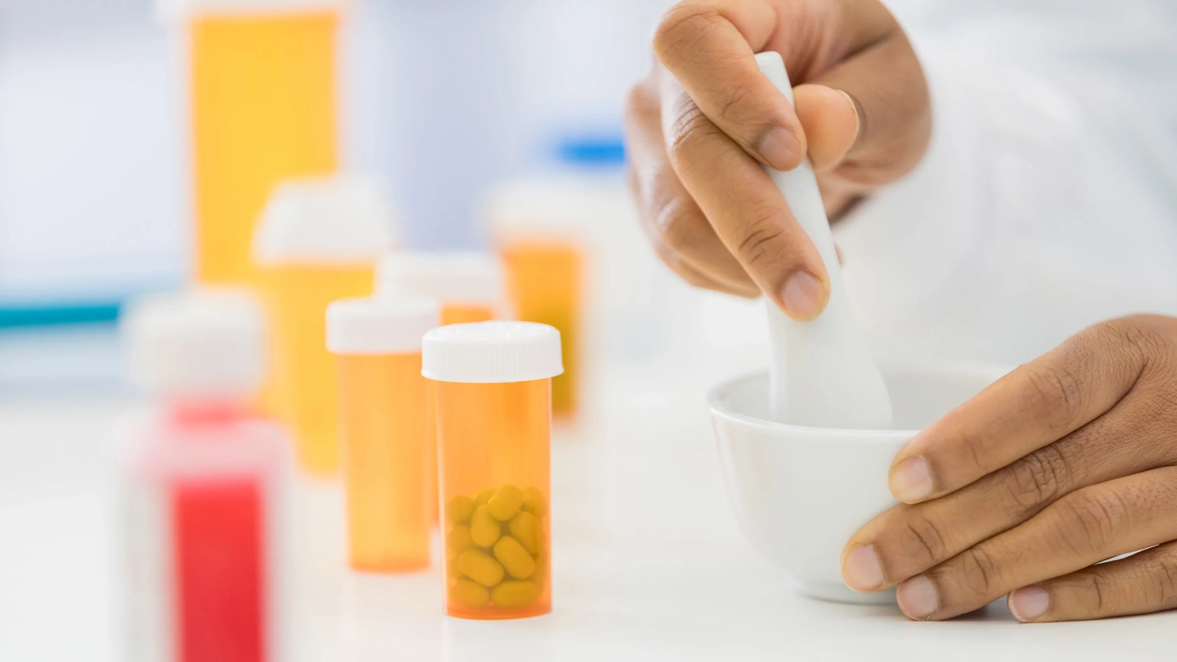 A close-up shot of a pharmacist compounding medications in a mortar.