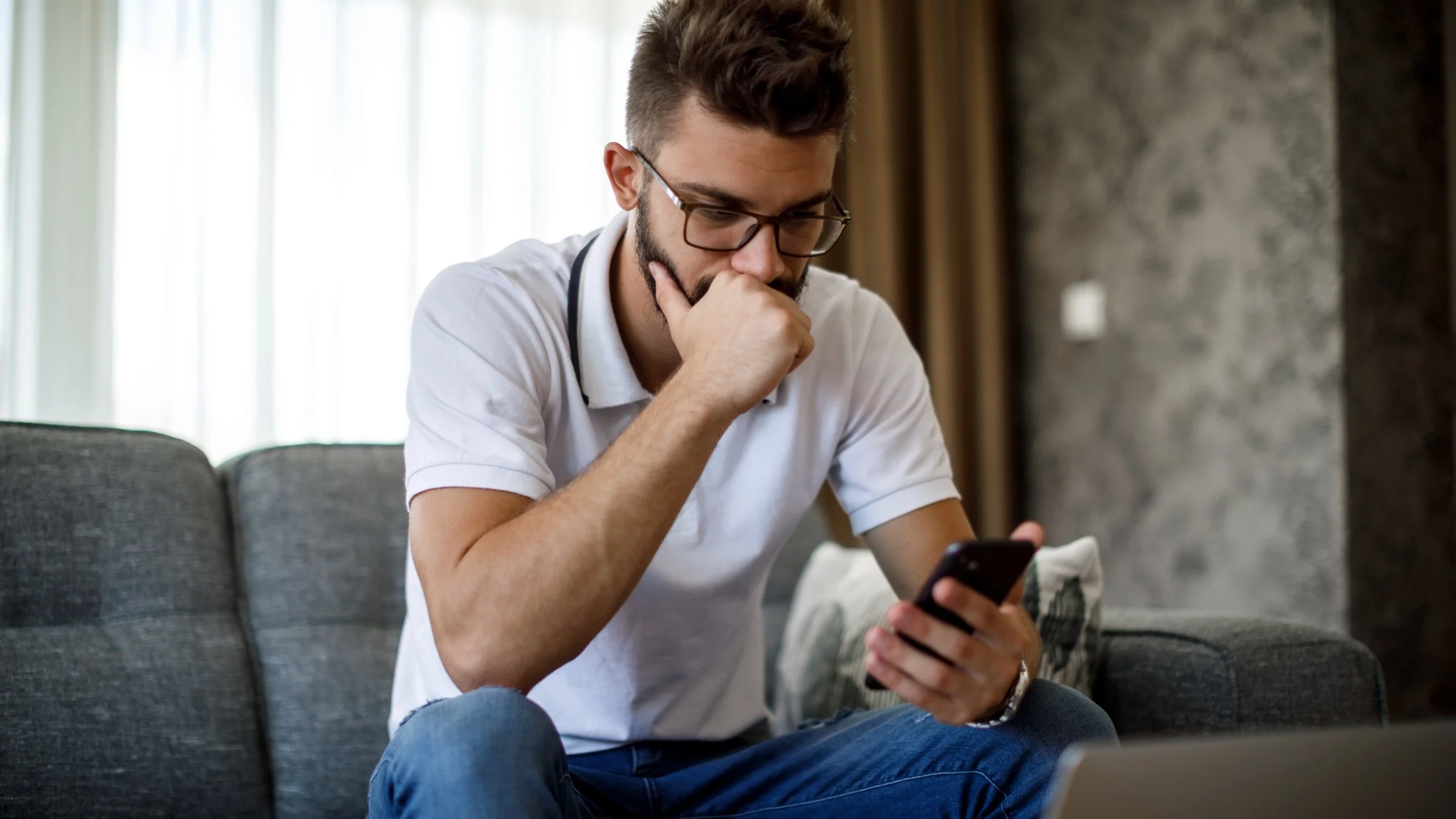 A person using their phone on their couch and thinking.