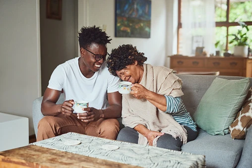 A grandmother and her grandson enjoying cups of coffee in the living room at home.