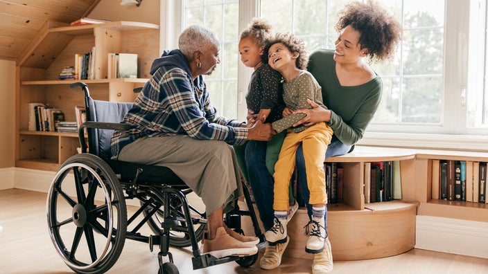 A grandmother in a wheelchair is spending time with her family.