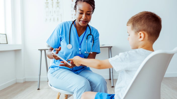 A doctor showing a child a digital tablet during a medical checkup.