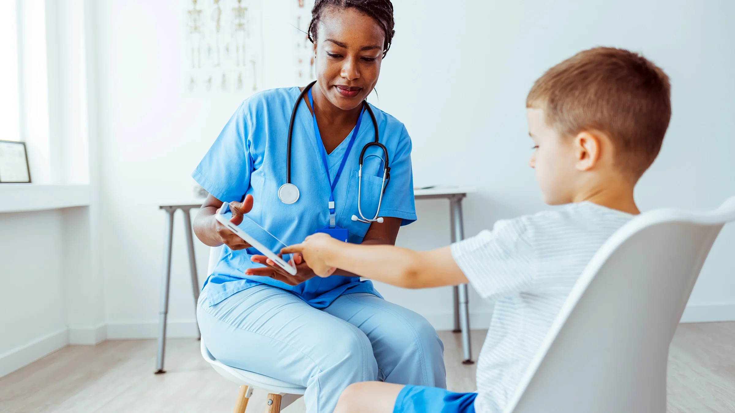 A doctor showing a child a digital tablet during a medical checkup.