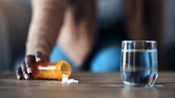 A woman pours pills onto a coffee table.
PeopleImages/iStock via Getty Images
