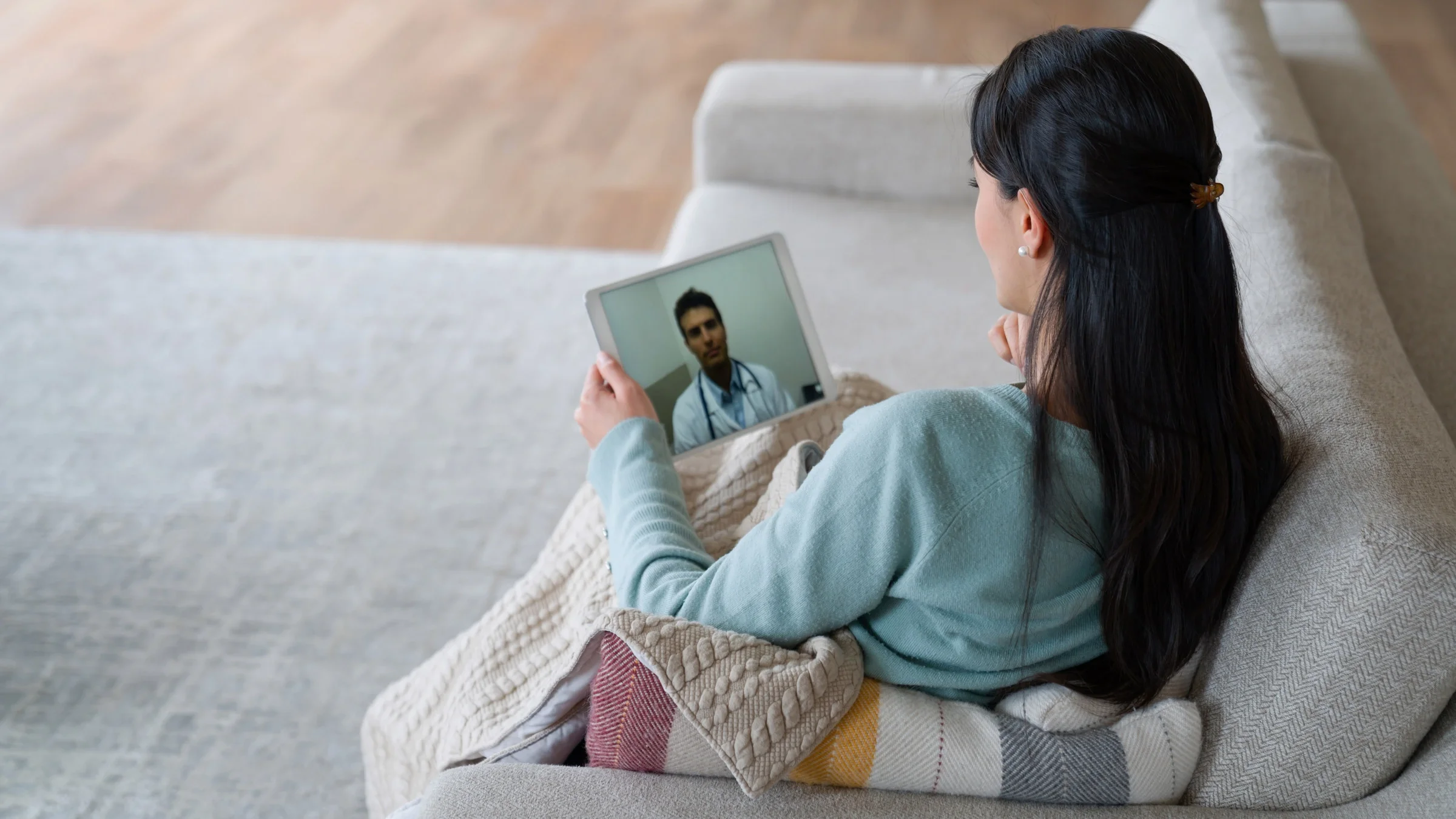 A patient talking to their doctor on a tablet from their couch.