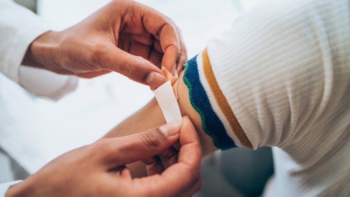 Close-up of a bandaid being applied after a vaccine.