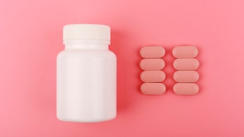 white pill bottle pink pills pink background-1328454848