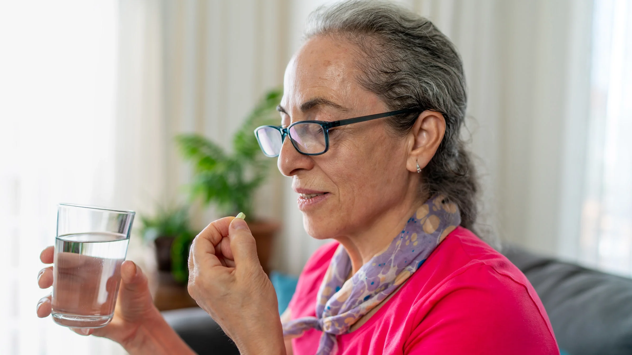 An older woman taking a pill.