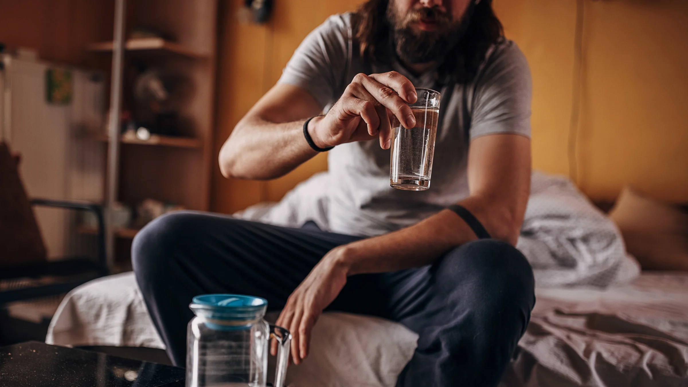 Cropped shot of someone sitting on their sofa bed and drinking water.