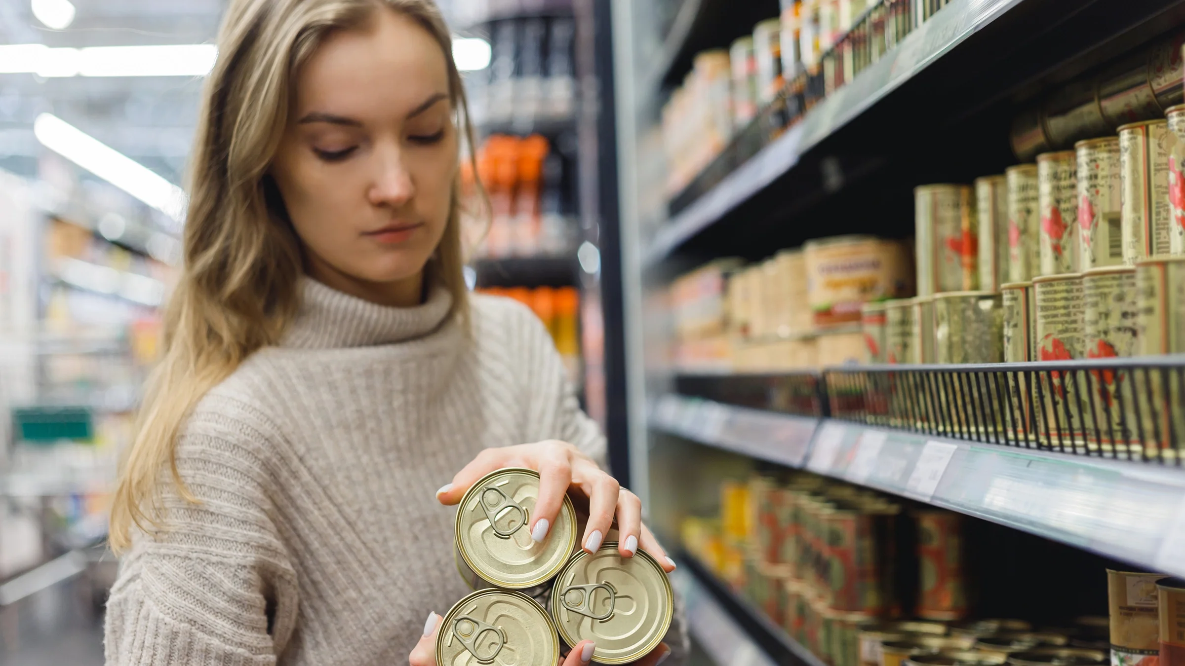 Woman buying canned goods in a supermarket.