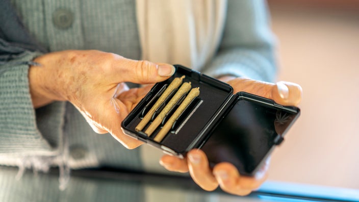 Close-up on a senior woman's hands holding a package of joints.