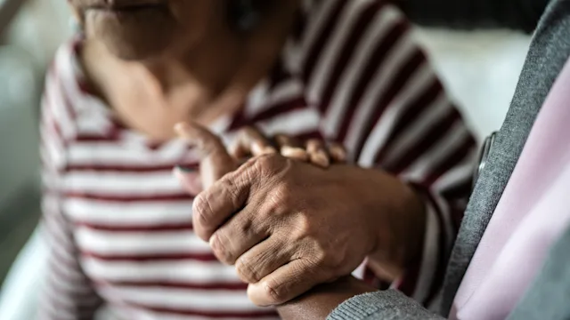 Dementia: Caregiving: closeup caregiver holding senior hand 1397344056