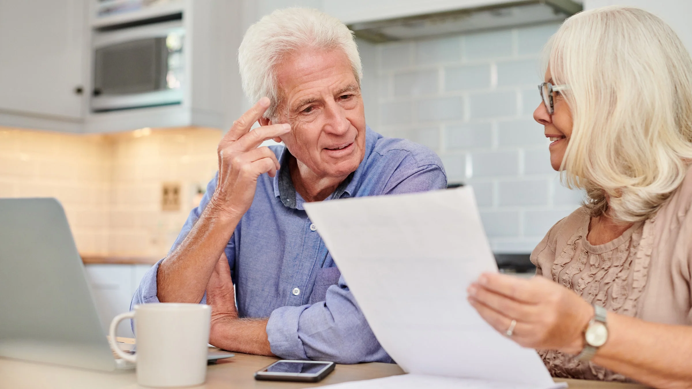 A senior couple doing their finances in their kitchen.