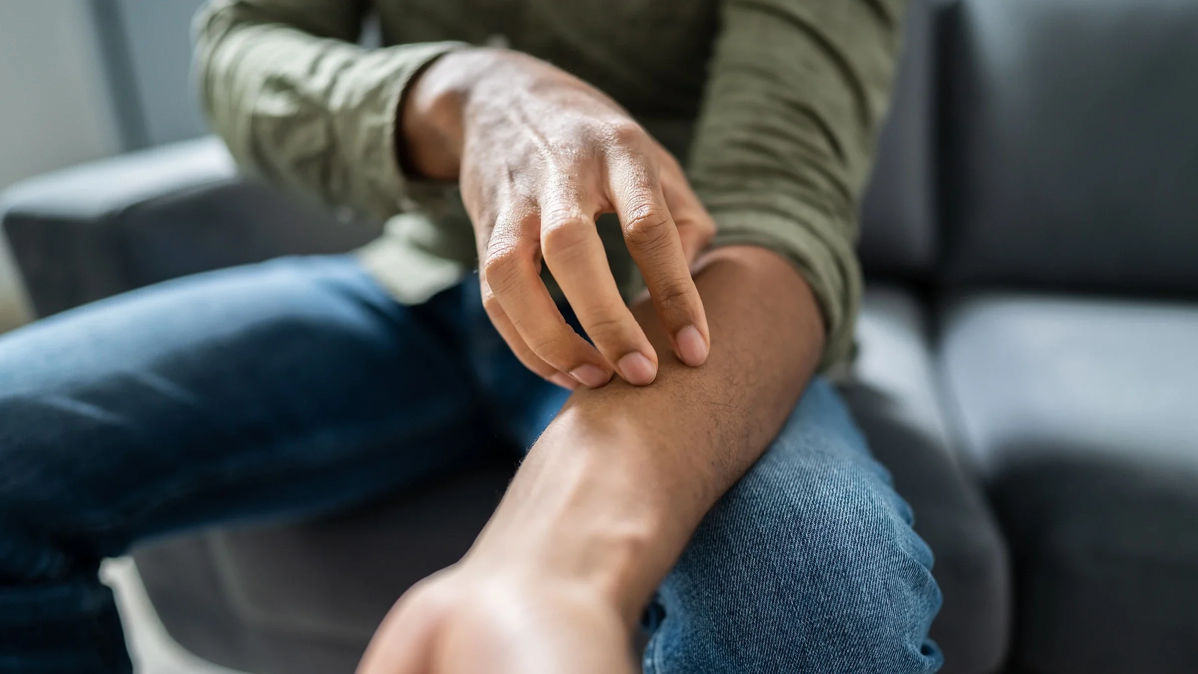 Cropped close-up of a man scratching an eczema patch on his arm.