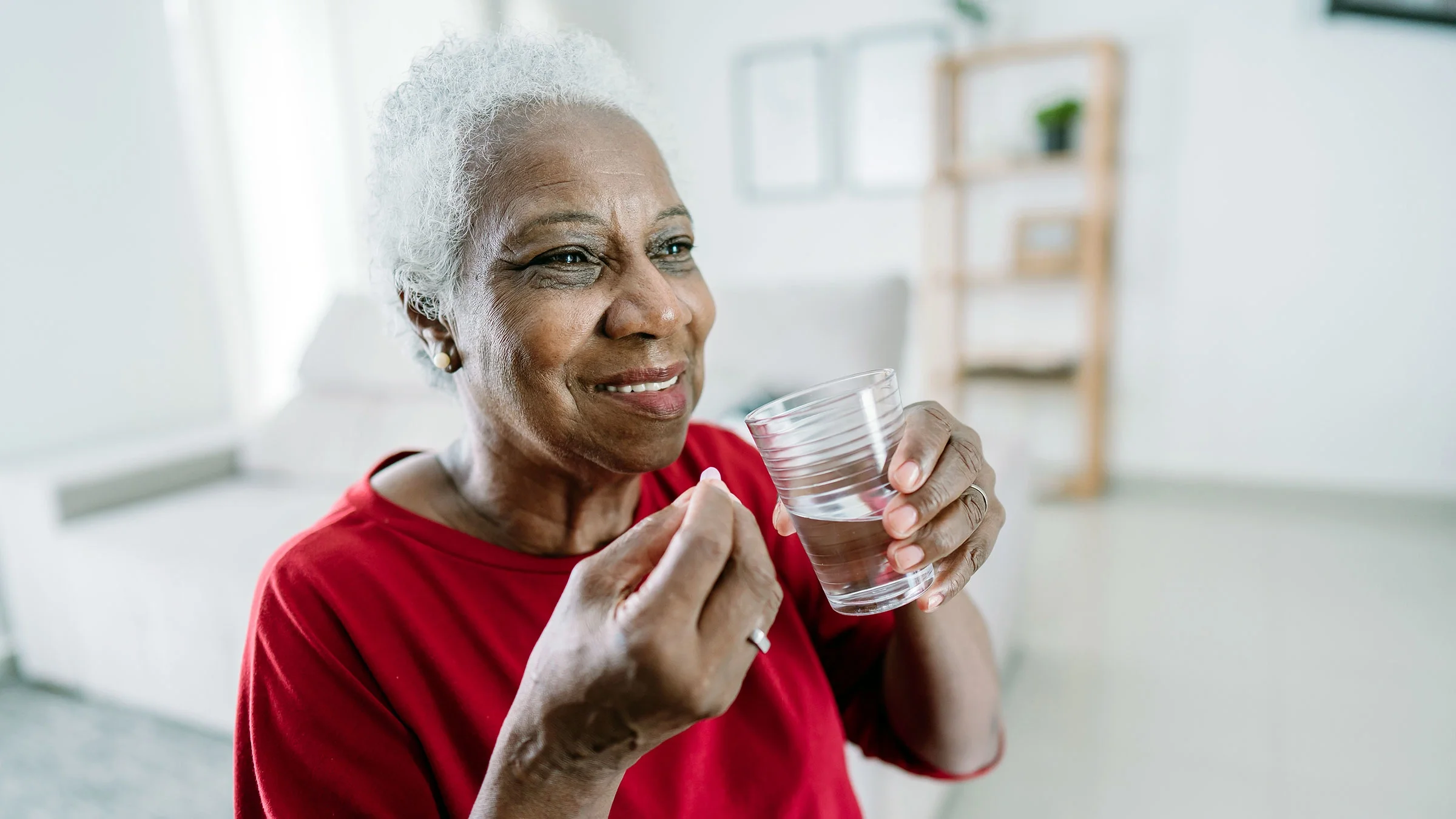 A woman prepares to take her medication as she holds a glass of water.