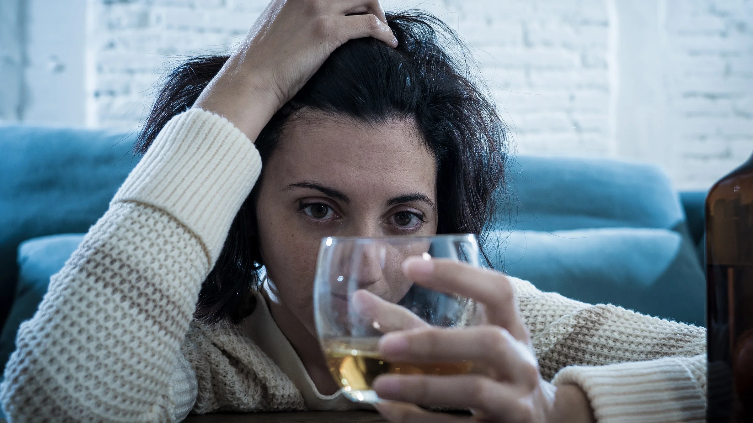 A woman drinks alcohol alone at home.