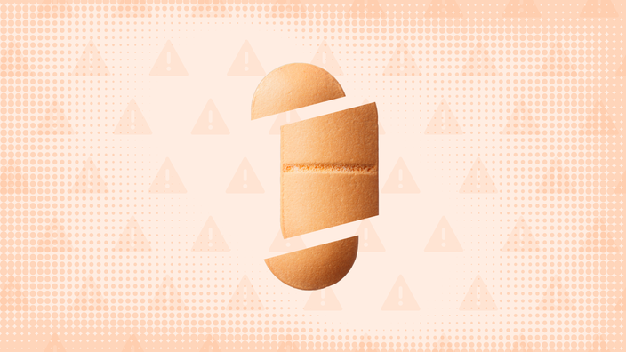 In the center of a light orange peach background with texture and warning sign pattern is a peach oblong pill cut into thirds. 