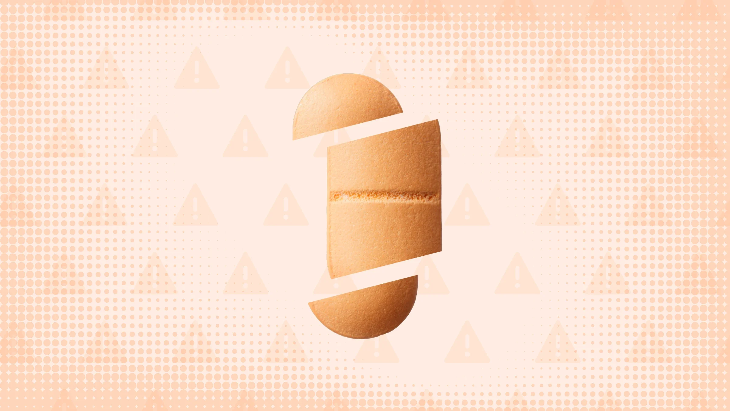 In the center of a light orange peach background with texture and warning sign pattern is a peach oblong pill cut into thirds. 
GoodRx Health