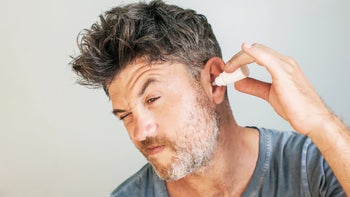 Ear infection: man using ear drops 957140496