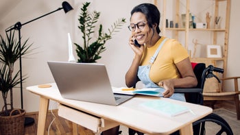 Low cost free healthcare: wheelchair user at desk on phone taking notes 1338010278
