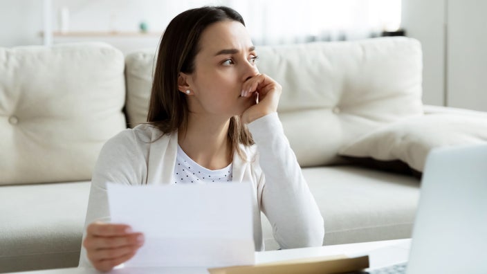 A frustrated woman holds a bill.