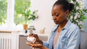 Pharmacy: woman pouring medicine into hand 2155828322