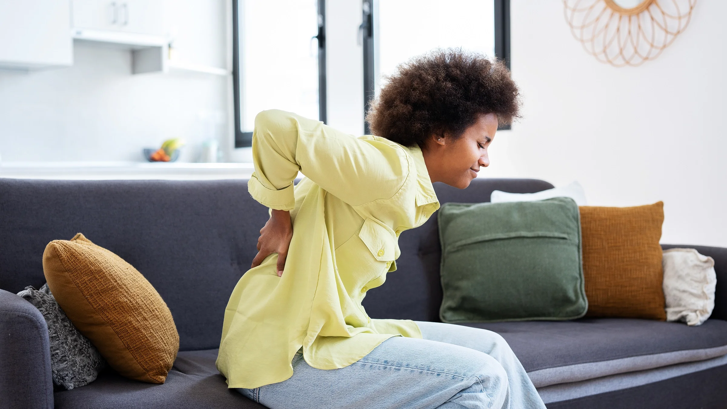 A woman has back pain. Extreme pain is one of the common symptoms of a sickle cell crisis, which can be triggered by different things like cold weather and dehydration. 