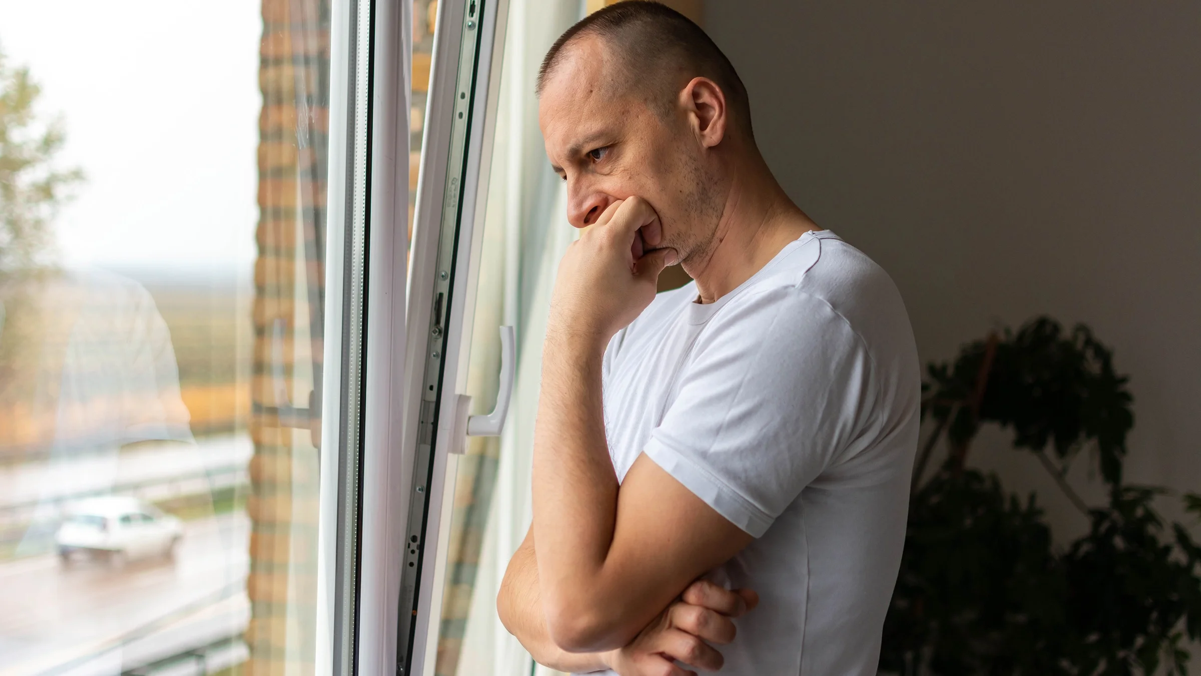 Man looking out the window in bedroom at home