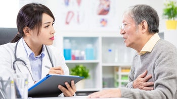 Medicare: Heart: older patient clutching chest doctor with clipboard 1159191756