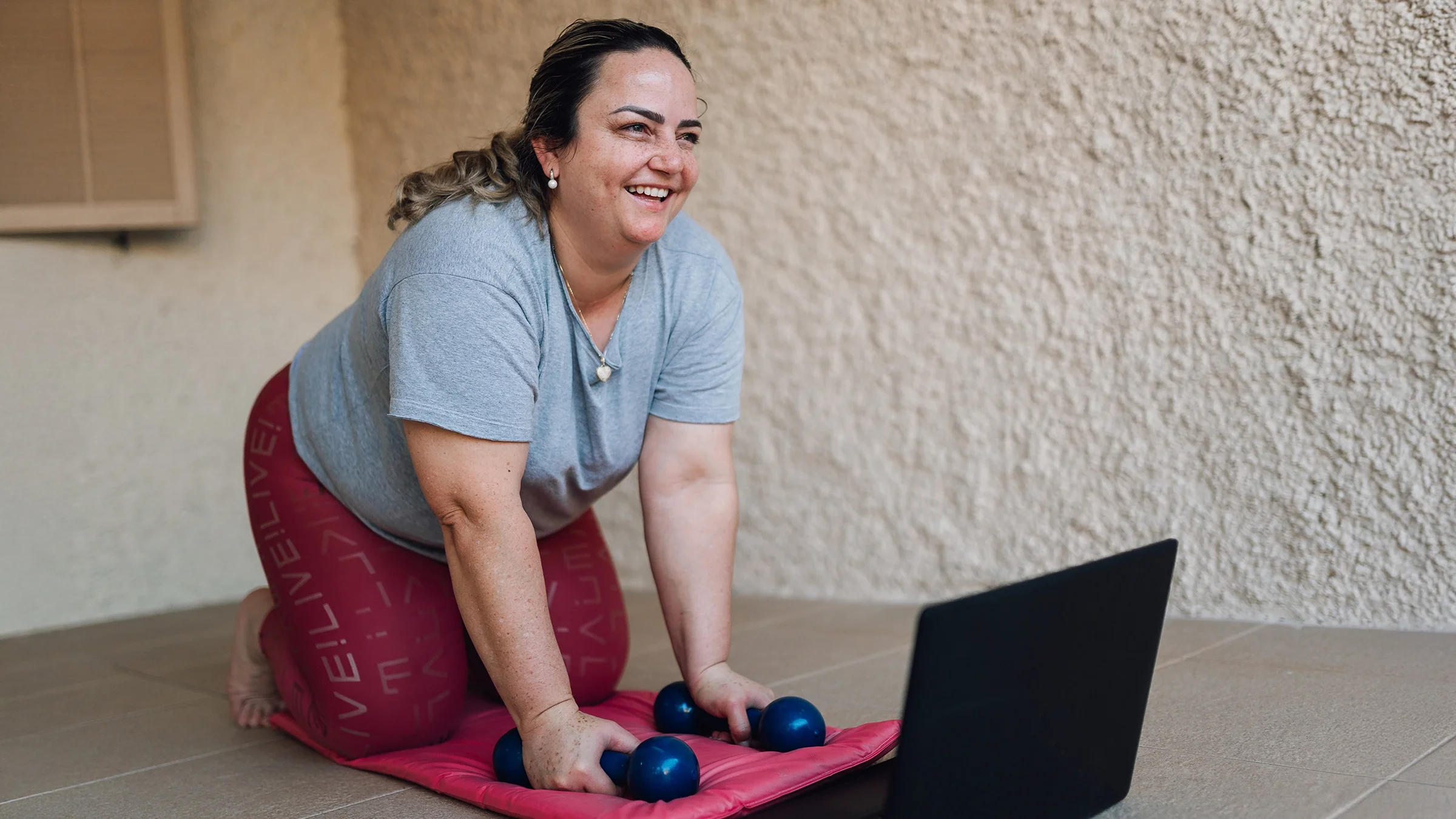 Woman using laptop for fitness workout at home.