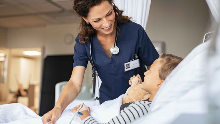 Medical professional talking with child patient in pediatrics ward.