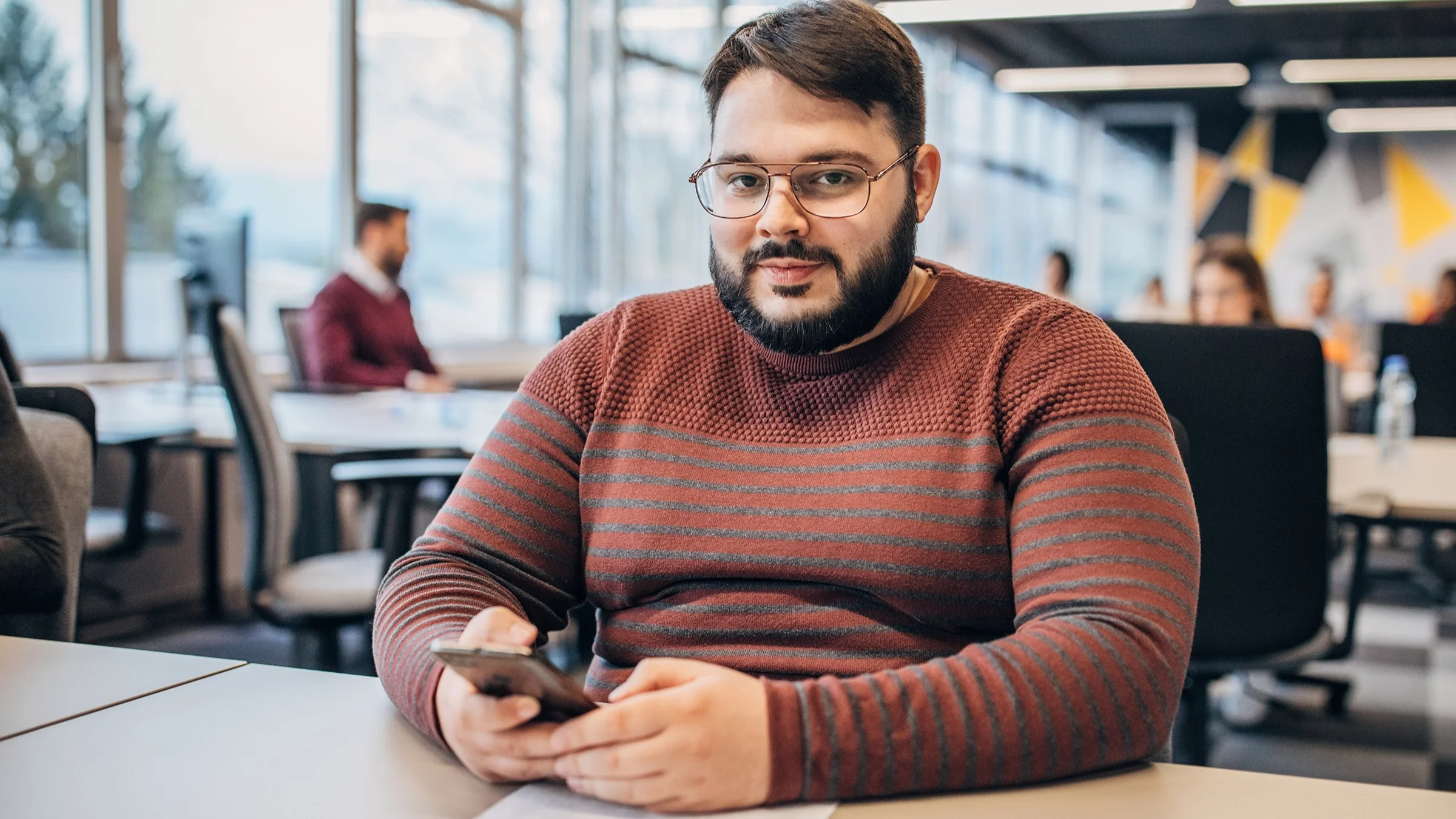 Portrait of a heavy set man with glasses on his photo at a conference table at work in an office.