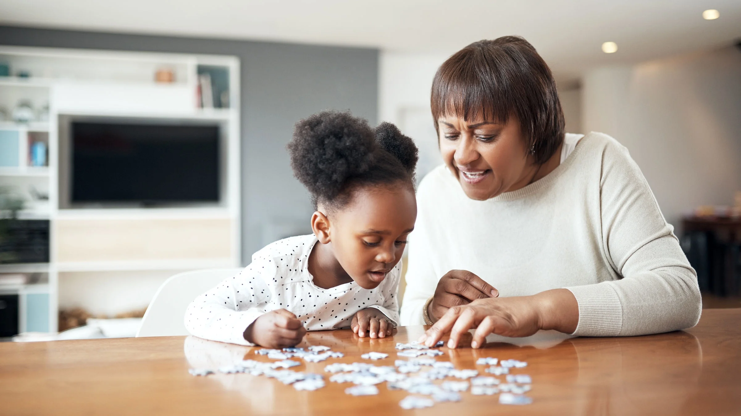 A woman and child are building a puzzle at home.