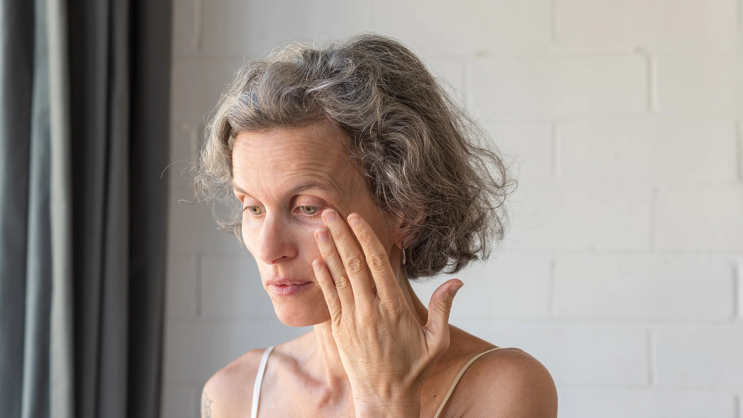 Senior woman rubbing her sore eye.