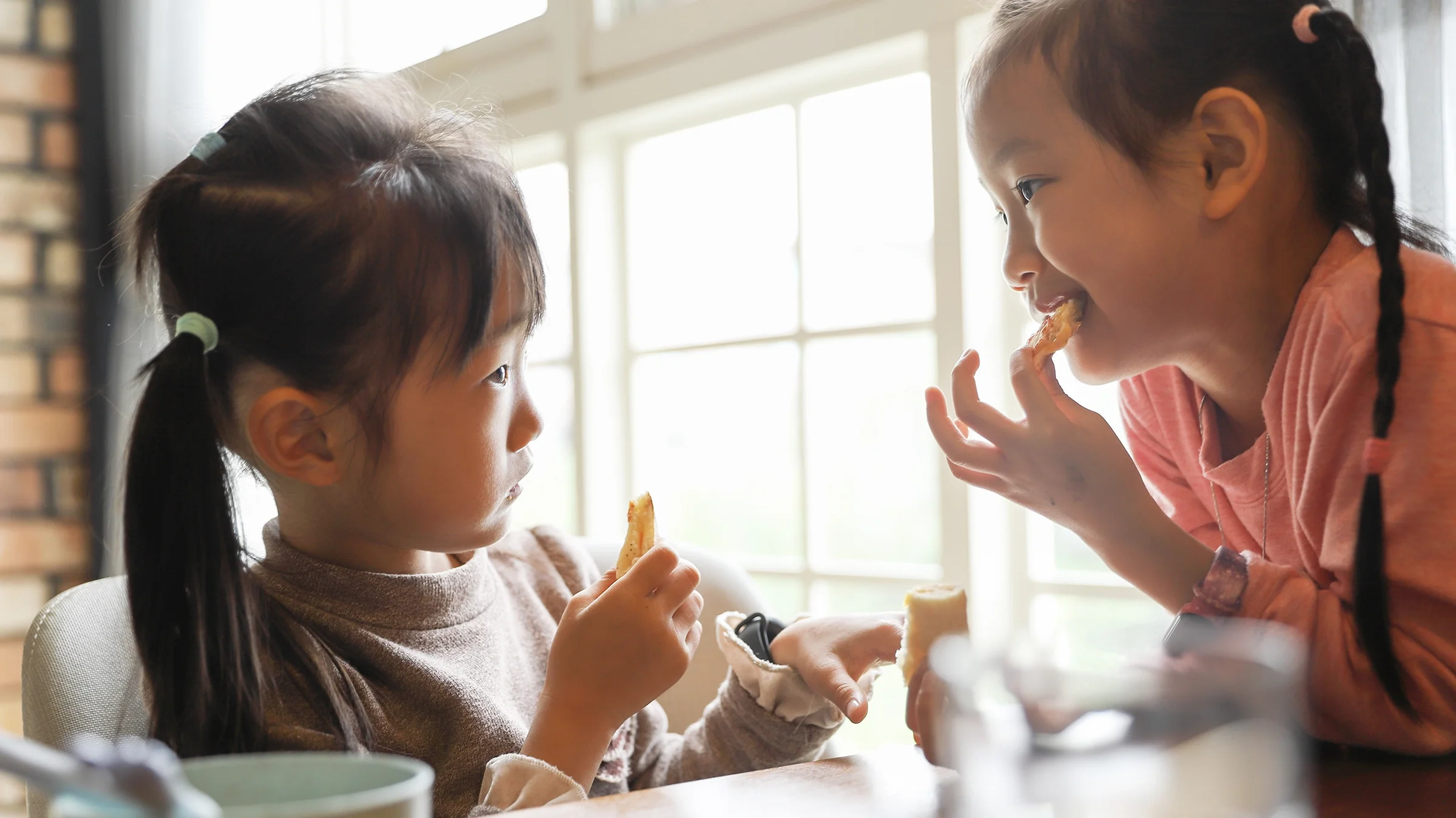 Two little girls are eating lunch in a restaurant.