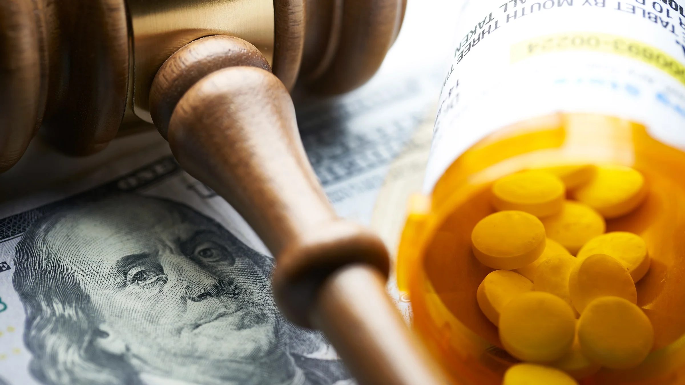 A pill bottle, dollar bills, and a gavel.
