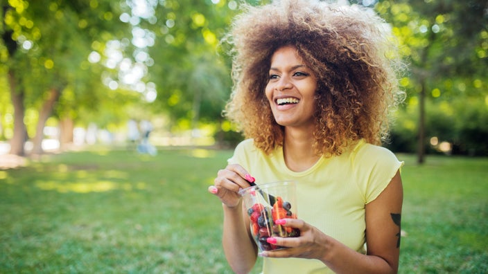 Woman sitting in park eating fruit 