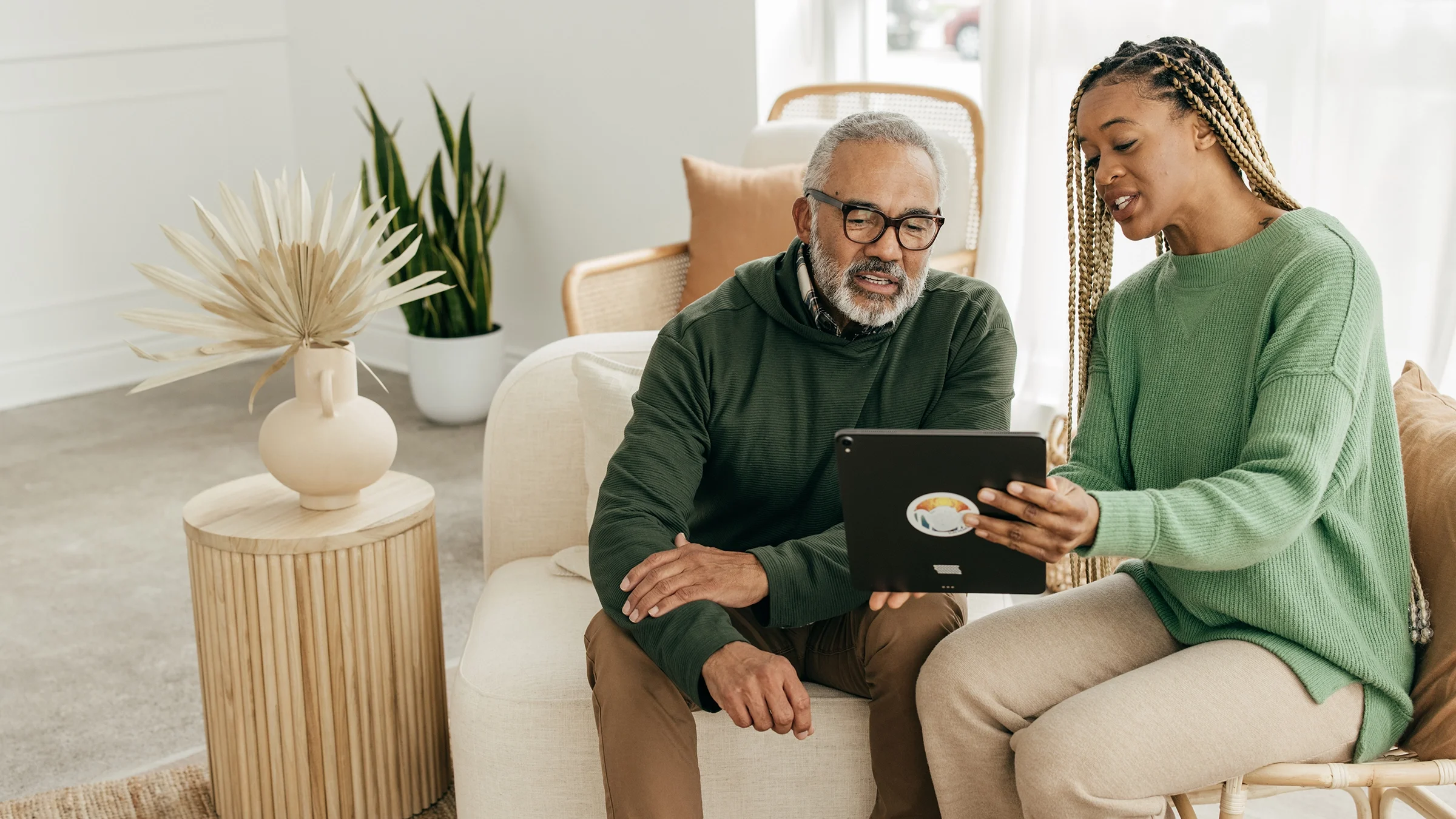 An older man and a woman are looking at a tablet computer.