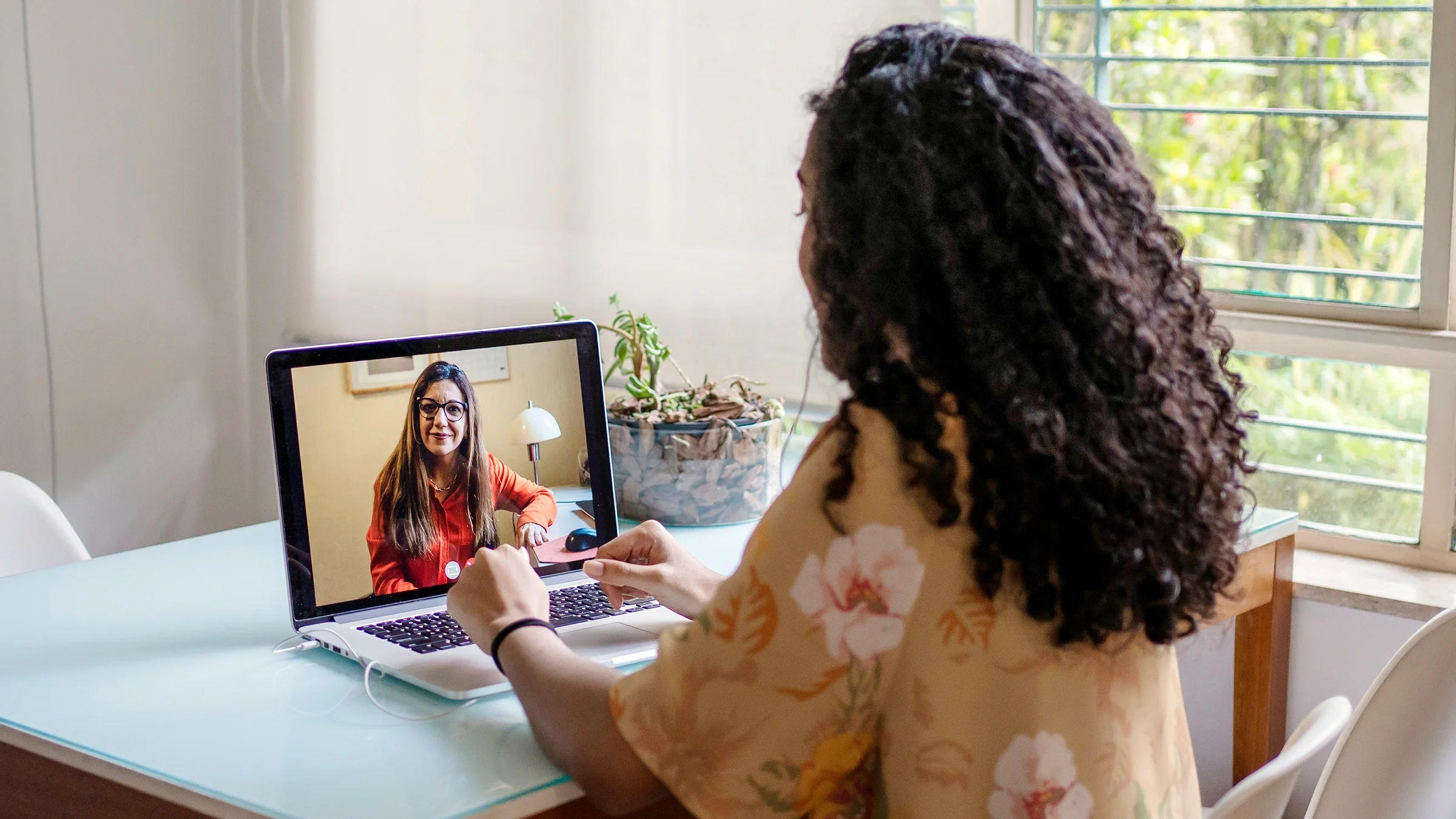 A woman talks to a therapist via video.
