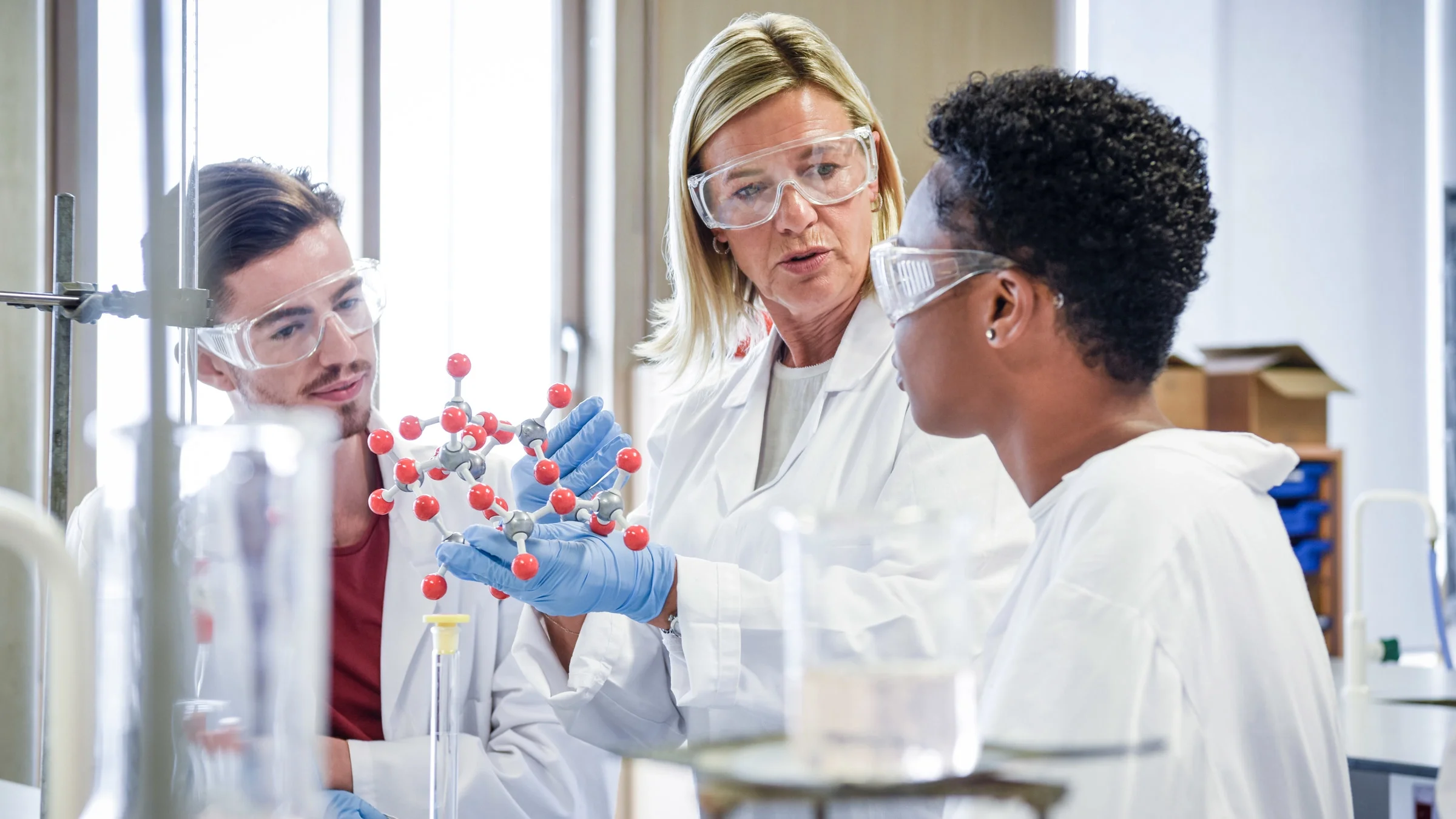 A professor and two students in a chemistry lab.