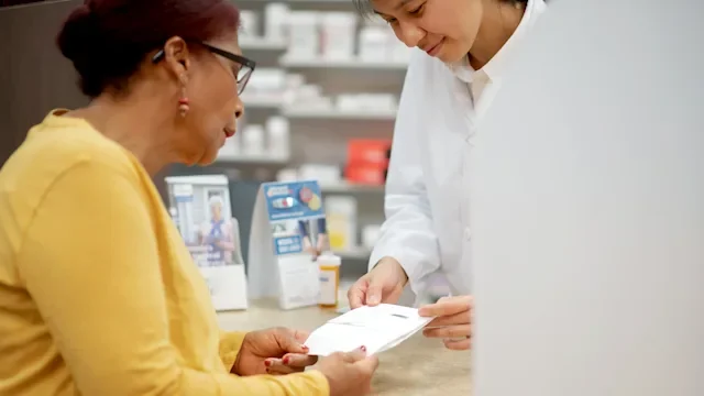 Pharmacy: woman picking up Rx 1182903306