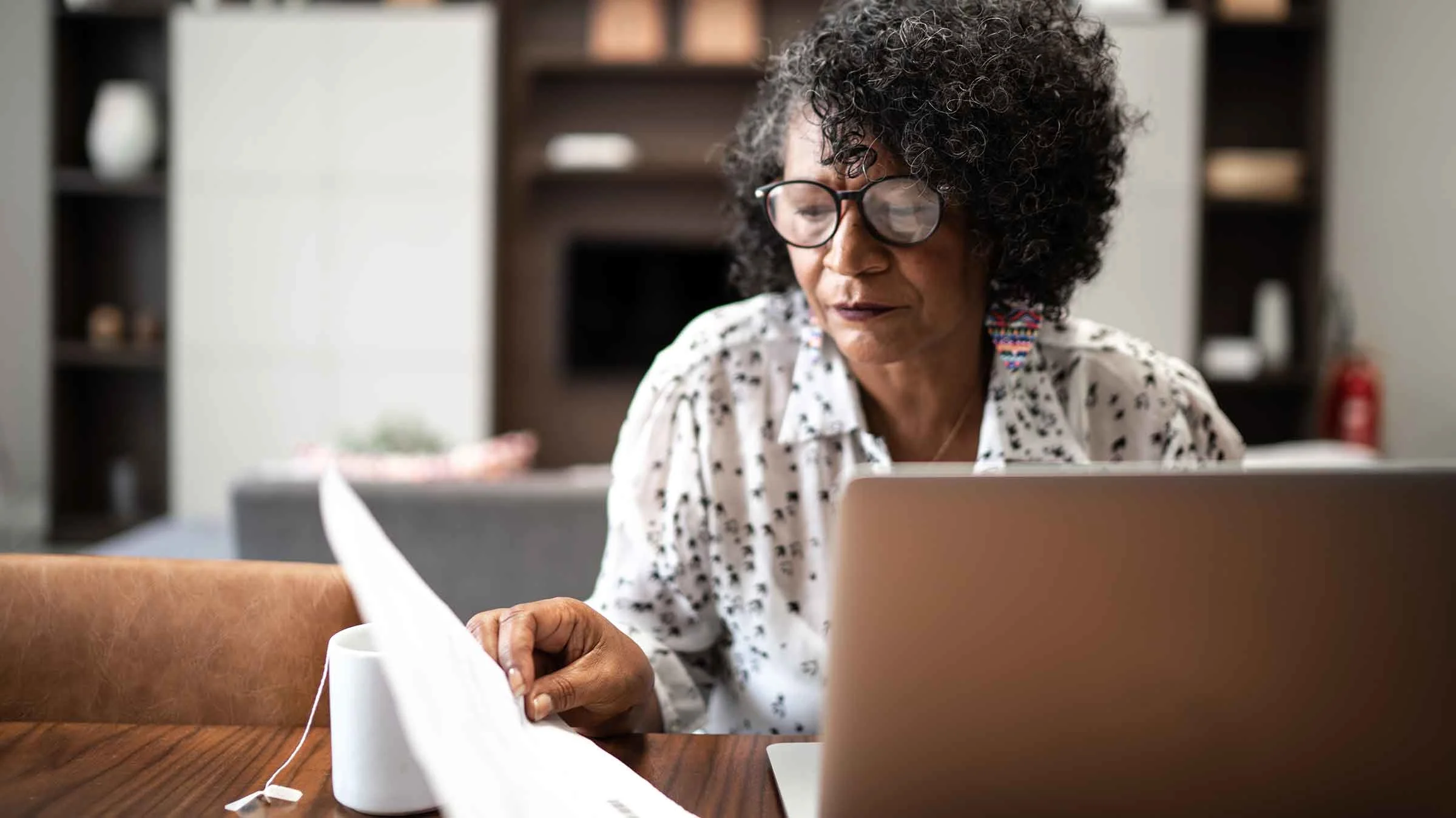 An older woman uses a laptop to work on her finances.